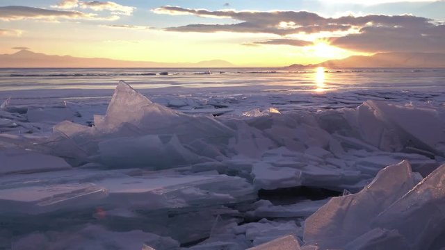 Dolly shot of gorgeous sunset over small icebergs and icicles in the frozen lake