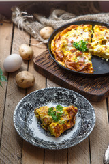 A piece of french baked omelette Savoy with ham, cheese, potato and leek on a plate, rustic style, top view