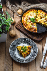 Omelette with bacon, potato, leeks and cheese on a plate, top view