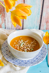 
Pumpkin, carrot and pepper soup. Blue wooden background. Orange tulip.
