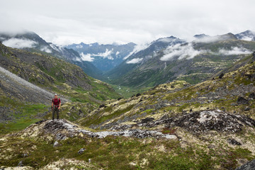 Obraz premium Hiker standing above glacial valley in Talkeetna Mountains, Alaska