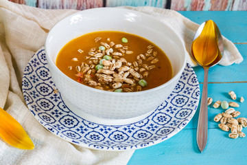 
Pumpkin, carrot and pepper soup. Blue wooden background. Orange tulip.