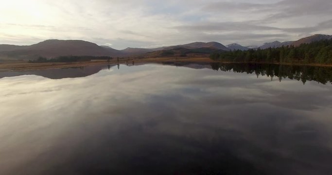 aerial footage of flying over a calm mirrorlike scottish loch in the remote highlands of scotland at loch tulla