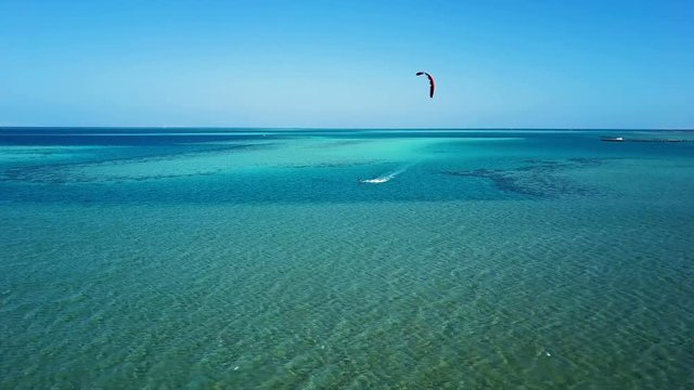Aerial view young man kite surfing in tropical blue ocean