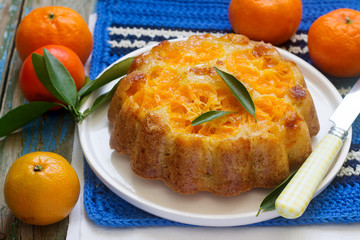 Mandarin cake and tangerines on rustic background.