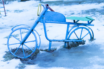 The old children's bike froze in the snow. Playground.