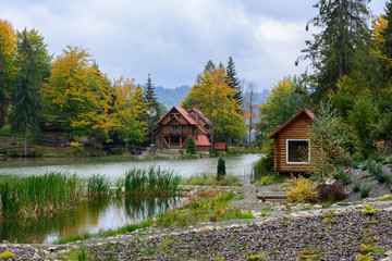 House near the lake in the forest, autumn day.  Leaf fall landscape.