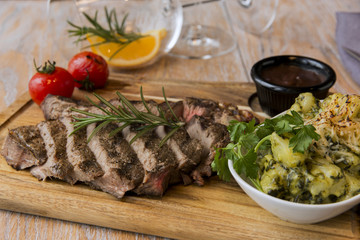 grill beef steak  with potatoes and tomatoes on a board 