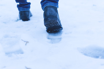 A man walks in the snow. Men's shoes. Close up.