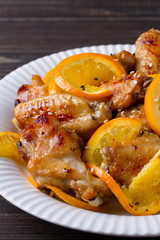 Sweet and sour chicken wings with oranges, served with sesame on white plate