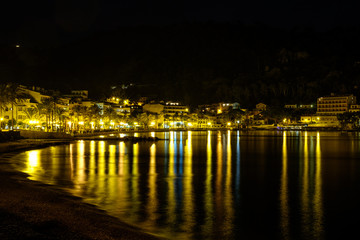  Mediterranean bay captured at night. Reflection of lights at sea. Yellow, blue, green. Palms. Hotels. Port de Soller, Mallorca.