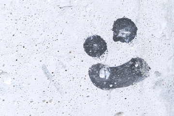 Drawing a malicious smile on white concrete wall