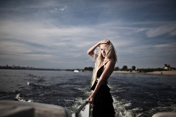 Fototapeta na wymiar blonde in black long dress floating on a yacht