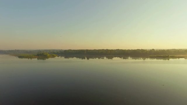 takeoff from the sandy beach at sunrise, 4k aerial view of morning river, Boat and old tree trunk on the sandy shore at the morning, aerial view of river at sunrise 4K