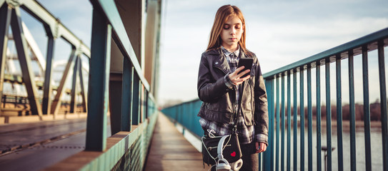 Obraz na płótnie Canvas A girl using smart phone and walking across the bridge