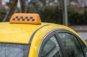 yellow taxi in the rain and checkered in passengers