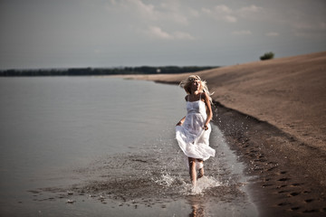 cheerful young girl running through water with splashes