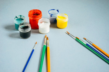 on a blue table lie jars with bright gouache and paint brushes