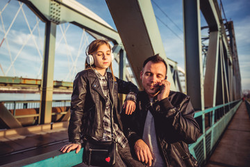 Father and daughter relaxing on bridge and listening music