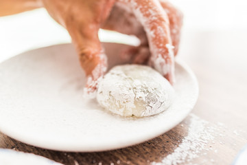 Hands shaping piece of mochi sticky glutinous rice cake dusted with starch flour to make dessert