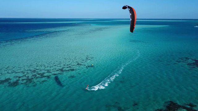Aerial view young man kite surfing in tropical blue ocean