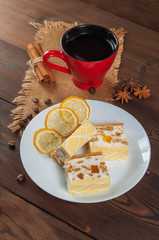 Red cup with coffee and lemon cake on a plate on sackcloth on a wooden table