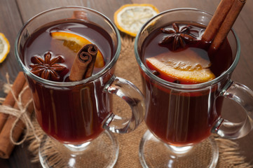 Red mulled wine on a wooden background with spices, close up