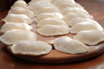 Fototapeta na wymiar Raw homemade vareniks on a cutting board. Ukrainian folk food.