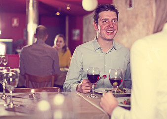 Smiling boyfriend with woman on dinner with wine