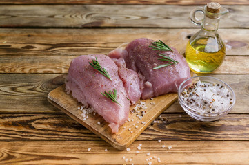 Fillet of a turkey on a chopping board. Spices, olive oil, fragrant herbs. Wooden rustic background