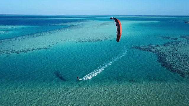 Aerial view young man kite surfing in tropical blue ocean