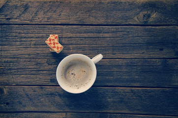 cup with hot coffee and sweets on the board surface