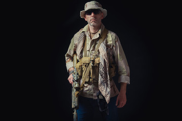 soldier of the American special forces in Afghanistan poses with a rifle on a black background