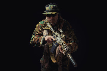 soldier of the American special forces in Afghanistan poses with a rifle on a black background