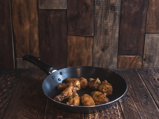 Chicken wings in a frying pan with fresh tomato