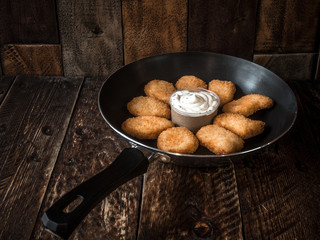 Freshly cooked nuggets in a frying pan with sauce