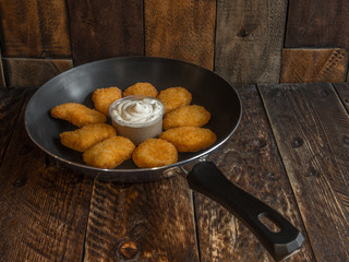 Freshly cooked nuggets in a frying pan with sauce