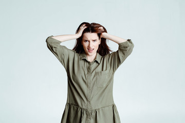 Beautiful young female brunette with long hair look plugging her ears being annoyed with noise wanting silence being exhausted of loud sound and shouting around her. portrait on a white background