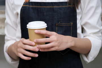 Barista hands holding a take away coffee cup with at cafe counter background, small business owner, food and drink industry concept