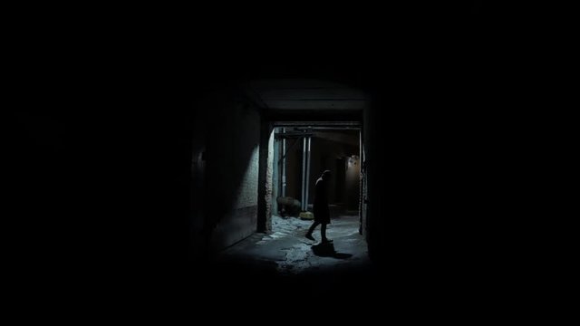 4k Man with coat walks at night street of dark noir cold city wide long shot