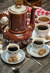 Caffeine design concept-old kettle for coffee, coffee cups on a wooden background with a white red cloth.