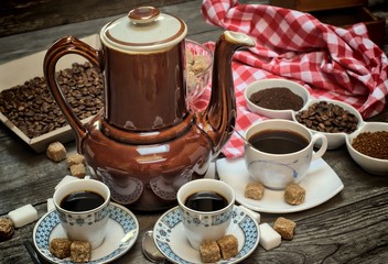 Caffeine design concept-old kettle for coffee, coffee cups on a wooden background with a white red cloth.