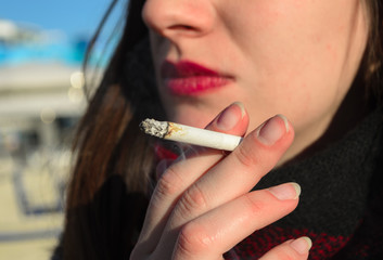 close up of woman smoking a cigarette - obrazy, fototapety, plakaty
