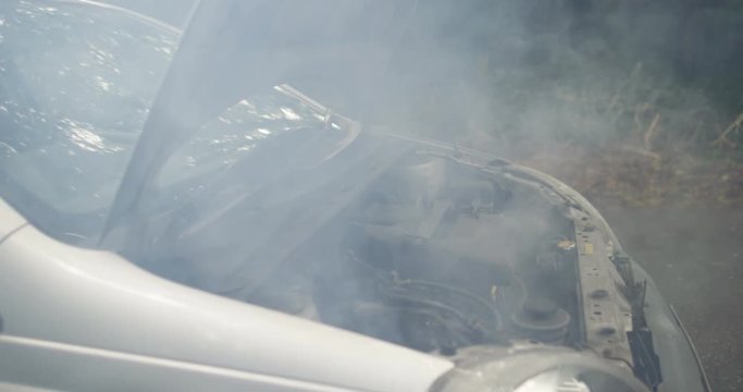 4k, Shot of an overheated car engine with smoke coming out of it. Slow motion.