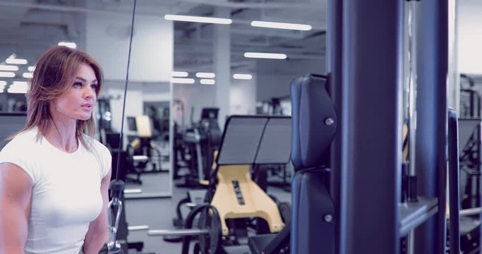 Adult woman doing Exercises for Tricep in fitness gym. Beautiful Woman doing triceps workout. Fitness girl doing triceps cable pushdown exercise in gym