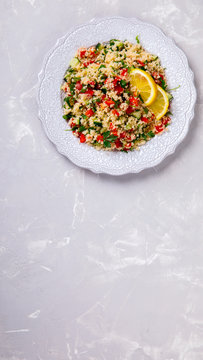 Tabbouleh salad with couscous on the plate.Traditional middle eastern or arab dish.Vegetarian.Parsley,pepper,cucumber,tomato,lemon.Middle eastern meze.Food or Healthy diet concept.Copy space for Text.