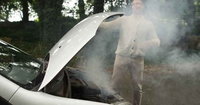 4k, Young African American man walks to look under the hood of a broken down car. Slow motion.