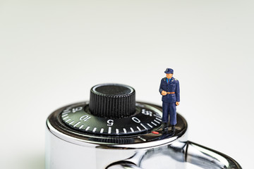 Computer security impact on IT business awareness concept, with miniature figure security guard standing on circle combination lock pad with turning code