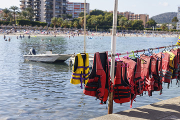 Gloves and boots for diving are on the shelf in the background of the sea and the beach with people