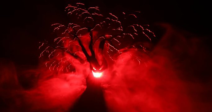 Silhouette of scary Halloween tree with horror face on dark foggy toned background with moon on back side. Scary horror tree with zombie and monster demon faces.